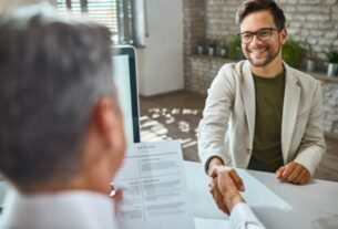 Deux personnes se serrent la main à travers un bureau, l'une d'elles tenant un CV.