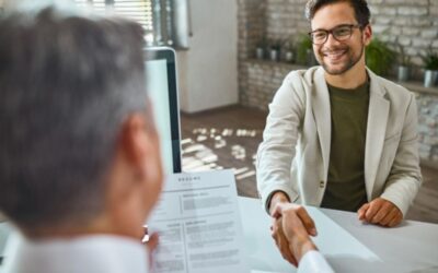 Deux personnes se serrent la main à travers un bureau, l'une d'elles tenant un CV.