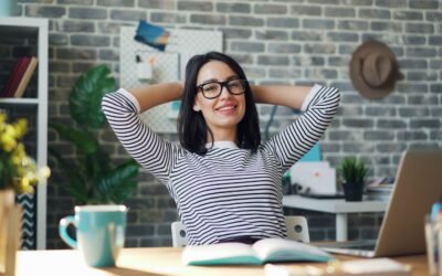 a woman sitting at a desk with her hands behind her head