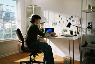 Person working at desk with laptop and phone.
