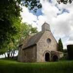 A quaint stone church sits peacefully under clouds.