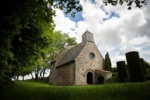 A quaint stone church sits peacefully under clouds.