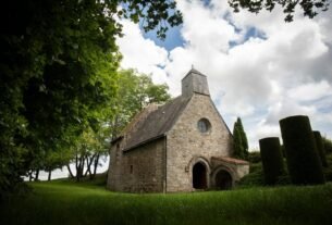 A quaint stone church sits peacefully under clouds.