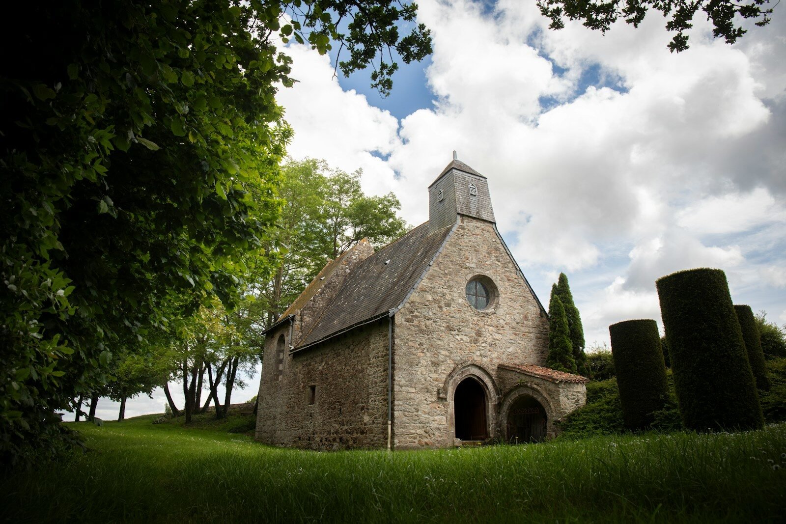 A quaint stone church sits peacefully under clouds.