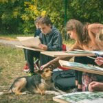 Children drawing outdoors with a dog nearby