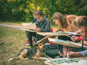 Children drawing outdoors with a dog nearby