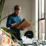 a man standing in an office holding a box