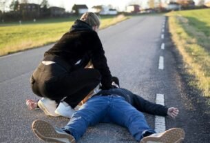 a man kneeling on the side of a road with another man kneeling on the ground