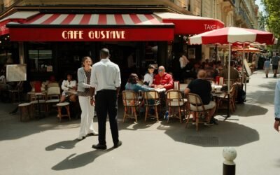 People sitting at tables outside Cafe Gustave on a sunny sidewalk in Paris
