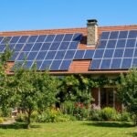 Toit de maison individuelle française avec panneaux solaires photovoltaïques, ciel dégagé, jardin