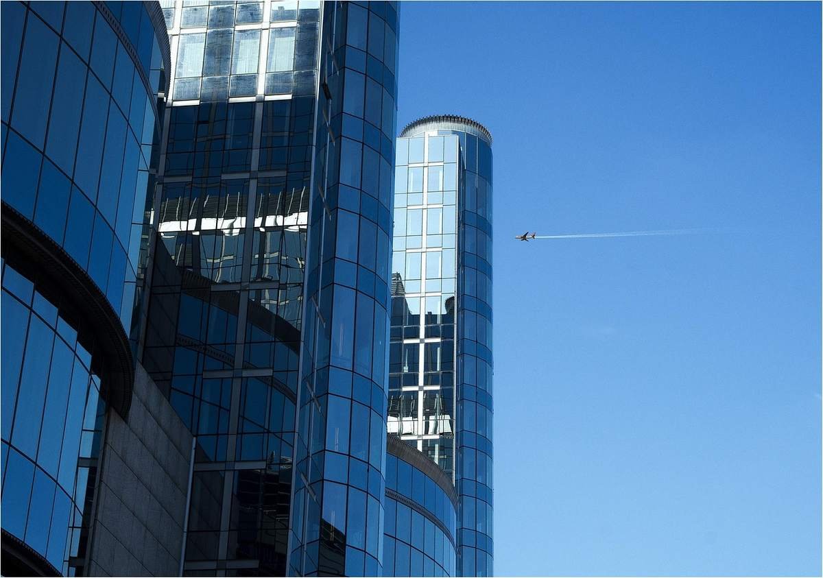 Des tours de verre modernes sous un ciel clair, avion en vol