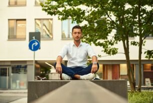 man in white dress shirt sitting on gray concrete bench during daytime